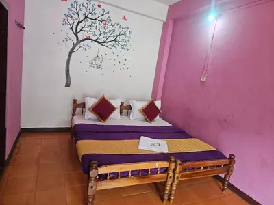 a bedroom with a bed with a tree mural on the wall at Cicily Cottage in Munnar