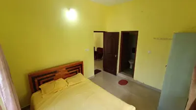 a bedroom with a bed in a yellow room at Pebbles in Kozhikode