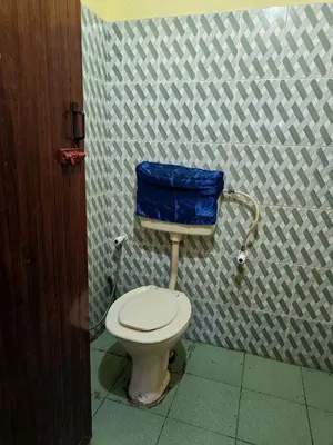 a bathroom with a toilet with a blue bag on it at Pebbles in Kozhikode