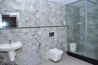 a bathroom with a sink and a toilet and a shower at Sanjose Residency in Virajpet