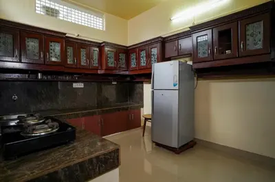 a kitchen with a refrigerator and wooden cabinets at Wayanad Palm Grove Retreat G Floor in Sultan Bathery