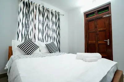 a bedroom with a white bed with black and white pillows at Wayanad Palm Grove Retreat G Floor in Sultan Bathery