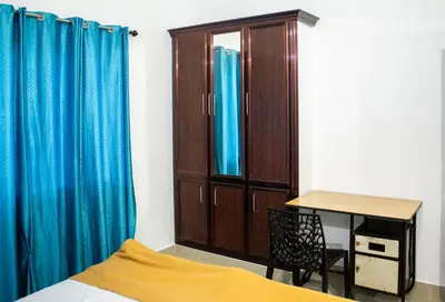 a bedroom with a bed and a desk and a cabinet at Padmanabhan's Homestay in Thrissur, Punkunnam in Trichūr