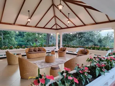 a conservatory with wicker chairs and tables and flowers at The Cana's Coorg in Ammatti