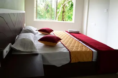 a bedroom with a bed with pillows and a window at The Green Room Residency in Padinjarathara