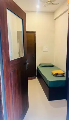 a small room with a door and a bed at The Green Room Residency in Padinjarathara