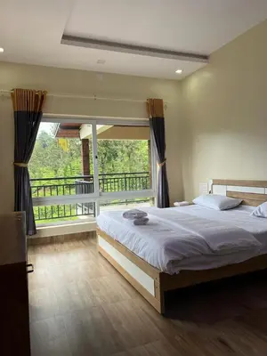 a bedroom with a large bed and a large window at Marina Homestay in Devāla