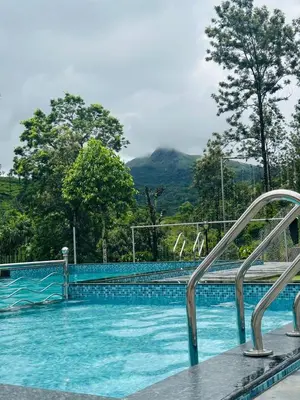 a swimming pool with a mountain in the background at Marina Homestay in Devāla