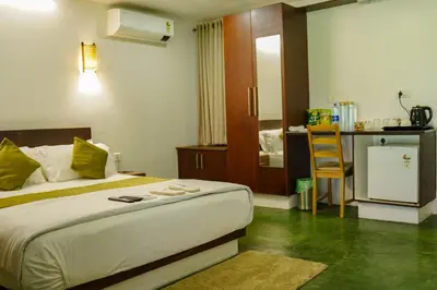 a bedroom with a bed and a kitchen with a table at Bamboo Grove in Mānantoddy