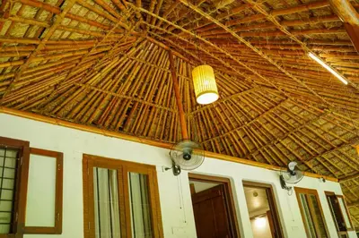 a room with a ceiling with a straw roof at Bamboo Grove in Mānantoddy
