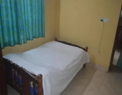 a small bedroom with a bed with white sheets at Kalpavruksha Farmstay by StayApart in Madikeri