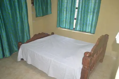 a bedroom with a bed with a white bedspread and two windows at Kalpavruksha Farmstay by StayApart in Madikeri