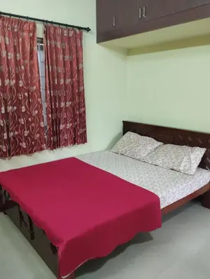 a bedroom with a bed with a red blanket on it at SHI's Isha Homestay in Coimbatore in Coimbatore