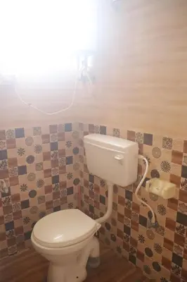 a bathroom with a toilet with a light above it at Coorg Northbreeze Estate stay in Madikeri