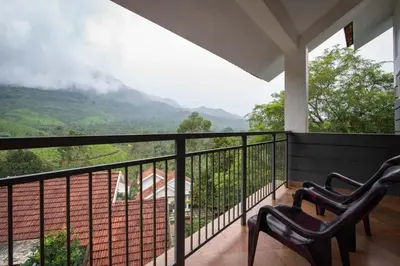 a balcony with two chairs and a view of a mountain at Dazzle Villa Resort in Kalpetta