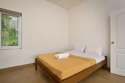 a bed in a white room with a window at Dazzle Villa Resort in Kalpetta