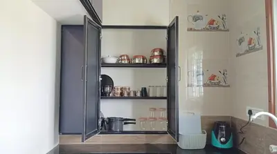 a kitchen with a glass cabinet with dishes on it at SHI's Peaceful Oasis near Isha Adiyogi, Kovai Kuttralam Waterfalls & Karunya University in Alāndurai