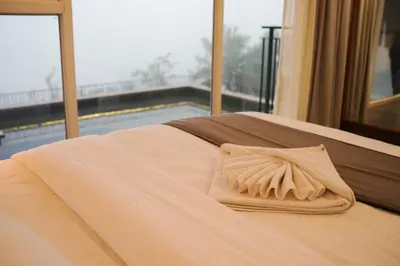 a bed with a white pillow on it with a window at Leaves Resort Vythiri Wayanad in Vythiri