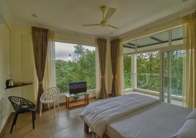 a bedroom with a bed and a large window at Ende Wayanad Resort in Koroth