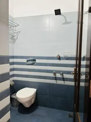 a bathroom with a toilet and blue and white stripes at Saaketh Holiday Home(2) in Kozhikode