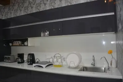 a kitchen with black cabinets and a sink and a counter at Earth - Luxurious 5 BHK AC Villa at Mysore in Mysore