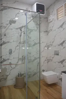 a bathroom with a glass shower with a toilet at Earth - Luxurious 5 BHK AC Villa at Mysore in Mysore