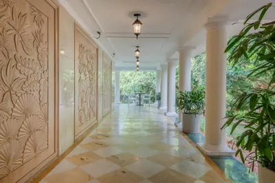 an empty hallway with columns and a wall with plants at Club Mahindra Golden Landmark, Mysuru in Mysore