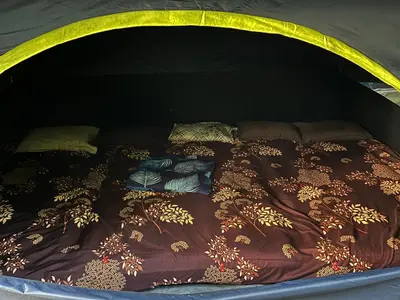 a bed with blankets and pillows on it at Dragster Tents in Kizhake Chālakudi