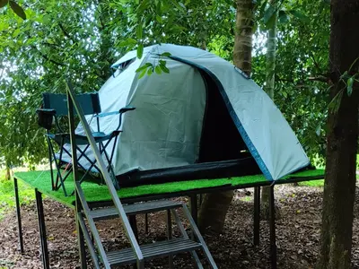 a tent sitting on a stand next to a chair at Dragster Tents in Kizhake Chālakudi