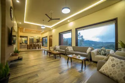 a living room with couches and tables and large windows at Sri Vidhya Residency by Indo Stays in Kotagiri