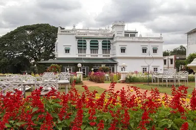 a white building with red flowers in front of it at The Green Hotel in Mysore