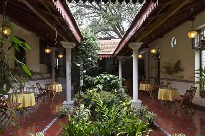 a patio with tables and chairs in a restaurant at The Green Hotel in Mysore