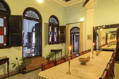 a large room with a table and chairs and windows at The Green Hotel in Mysore