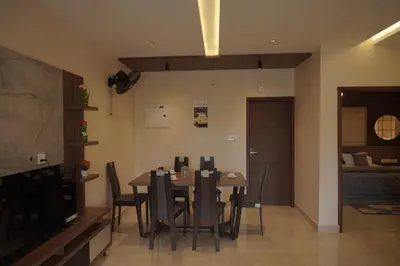 a dining room with a table and chairs and a television at Ncomforts Luxurious Apartments in Perintalmanna