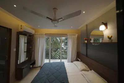 a bedroom with a bed with a ceiling fan and a window at Ncomforts Luxurious Apartments in Perintalmanna