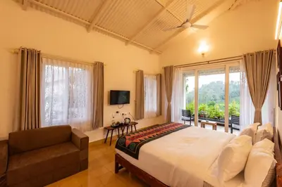 a bedroom with a bed and a couch and a window at Ibex Resorts, Kotagiri in Kotagiri
