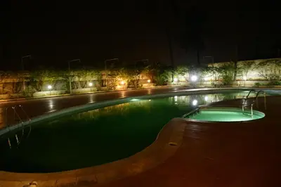 a large swimming pool at night with lights at Nijaguna Resorts in Chāmrājnagar