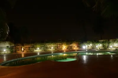 a swimming pool at night with lights at Nijaguna Resorts in Chāmrājnagar