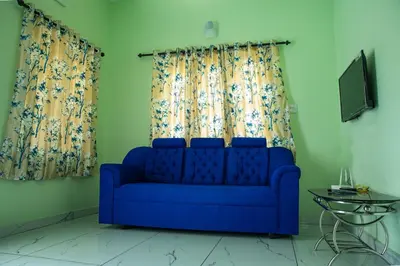 a blue couch in a living room with curtains at DREAMS VILLA Near Rajagiri Hospital in Alwaye