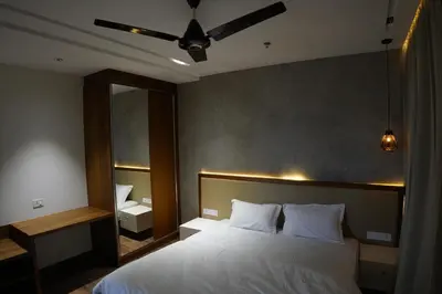 a bedroom with a white bed with a large mirror at Royal Holidays & Stays in Pattāmbi