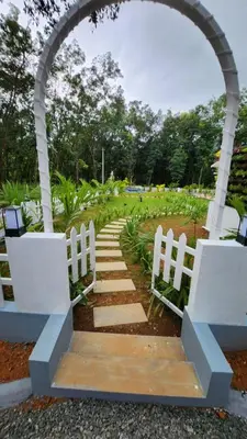 an archway with white chairs and a pathway at Merlys Fruit Garden - Resort at Thattekkad in Kotamangalam