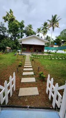 a path in front of a building with a white fence at Merlys Fruit Garden - Resort at Thattekkad in Kotamangalam