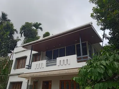 a white house with a black roof at High shine Homestay in Meppādi