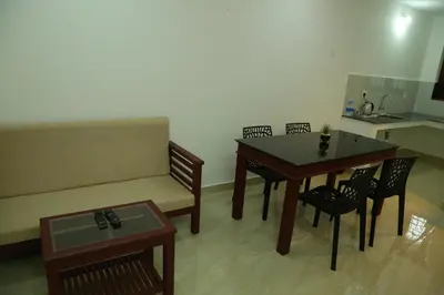 a living room with a couch and a table and chairs at Grace Mary Residency in Nedumbassery