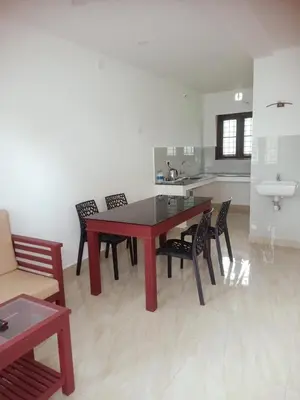 a red table and chairs in a room with a kitchen at Grace Mary Residency in Nedumbassery