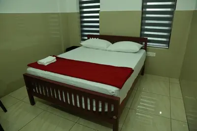a bed with a red blanket and white pillows at Grace Mary Residency in Nedumbassery