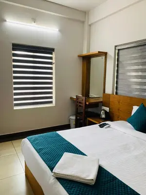 a bedroom with a bed with a mirror and a window at Regalia Wayanad in Kalpetta