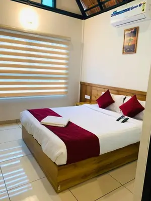a bedroom with a large bed with red pillows at Regalia Wayanad in Kalpetta