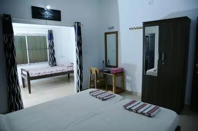 a bedroom with a bed and a chair and a mirror at Ocean Green Kerala in Kannur