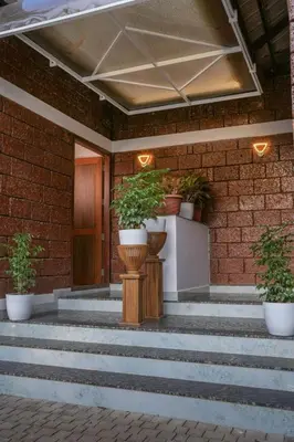 a brick building with stairs and potted plants on it at Redstone Villa in Tāzhekkod
